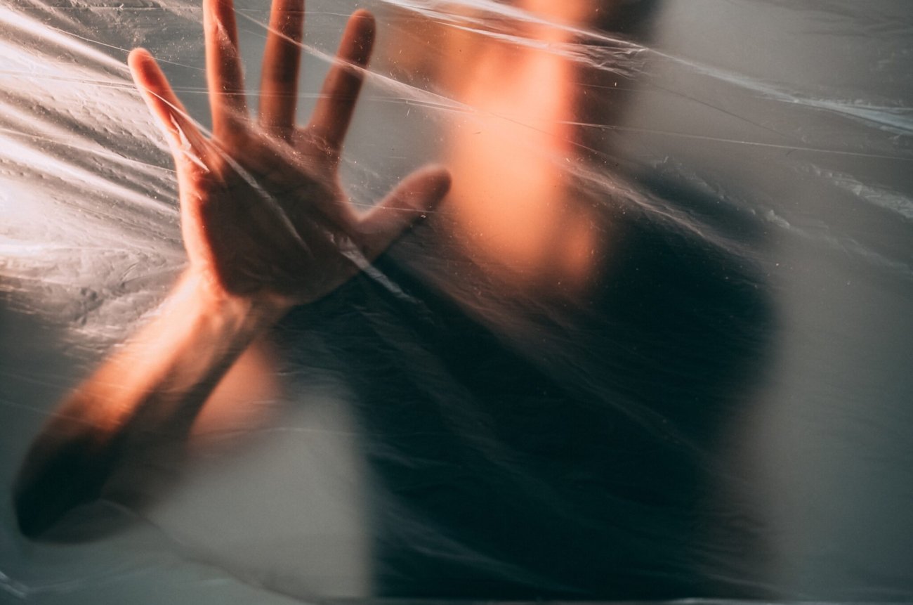 A man behind a plastic bag touching it with his palm